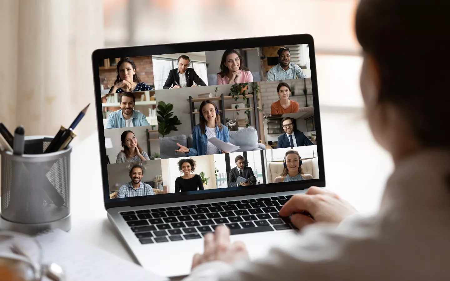 Person participating in a virtual team meeting on a laptop, with multiple people visible on the screen.