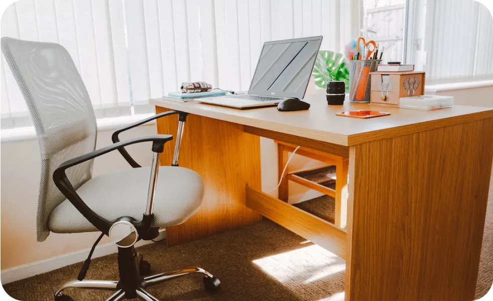 Clean and organized office desk with a laptop, pens, books, and other stationery items